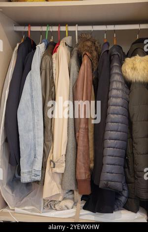 Ein Kleiderschrank mit verschiedenen Mänteln und Jacken in verschiedenen Farben und Materialien, einschließlich Denim, Leder und Pufferstilen Stockfoto