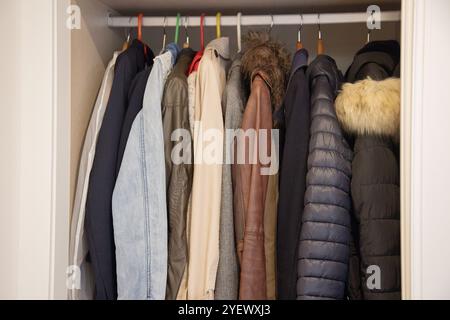 Ein Kleiderschrank mit verschiedenen Mänteln und Jacken in verschiedenen Farben und Materialien, einschließlich Denim, Leder und Pufferstilen Stockfoto