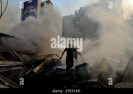 Beirut, Libanon. November 2024. Zivilschutzarbeiter sind in Rauch verwickelt, wenn sie versuchen, das Feuer von Autos und zerstörten Gebäuden abzuschütteln, die von israelischen Luftangriffen auf den südlichen Vorort Beiruts, einer Brutstätte der pro-iranischen Hisbollah-Partei, angegriffen wurden. (Kreditbild: © Marwan Naamani/ZUMA Press Wire) NUR REDAKTIONELLE VERWENDUNG! Nicht für kommerzielle ZWECKE! Stockfoto