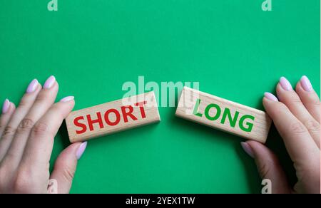 Symbol kurz vs lang. Konzeptwort kurz vs lang auf Holzblöcken. Geschäftsmann Hand. Schöner grüner Hintergrund. Business und kurz- vs Langkonzept. C Stockfoto
