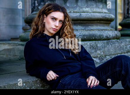 Das schöne weibliche Model Ava Nicholson entspannt sich auf der Treppe des neoklassizistischen Dundee Camperdown House, geschützt vor der Herbstsonne, Schottland Stockfoto