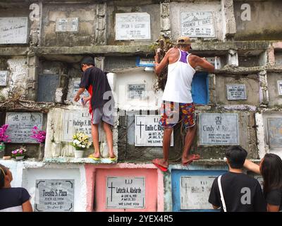 Navotas, Philippinen. November 2024. Ein kleiner Junge und sein Großvater zünden Kerzen am Grab ihres verstorbenen Verwandten an. Filipinos strömen zu verschiedenen Friedhöfen, um UNDAS oder Allerheiligen in verschiedenen Teilen der Philippinen zu begehen. Sie bieten Blumen und Kerzen an, die an die Gräber ihrer verstorbenen Verwandten gelegt werden. Quelle: SOPA Images Limited/Alamy Live News Stockfoto