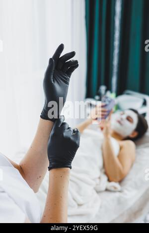 Weibliche Hände Nahaufnahme in latexschwarzen Handschuhen. Eine Frau zieht medizinische Handschuhe an. Stockfoto