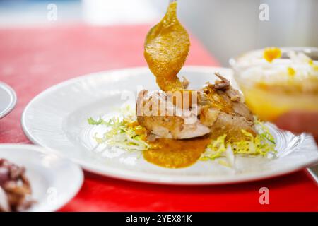 Der Koch gibt etwas Sauce über Wachteln in einen Salat Stockfoto