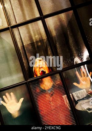 Mann, der hinter einer verglasten Tür oder einem Fenster schreiend mit Händen gegen das Glas gedrückt und unglücklich oder frustriert aussieht. Stockfoto