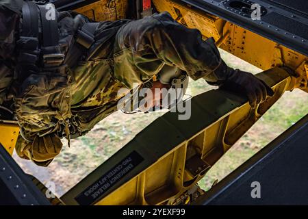 Adam Osip, ein Hubschrauberreparateur der CH-47, der dem 2. Bataillon, 104. Aviation Regiment, zugeteilt ist, schaut durch die zentrale Laderaumluke eines CH-47F Chinook Transporthubschraubers, während er sich auf die Landung in einer provisorischen Hubschrauberlandezone in Berlin, Connecticut, vorbereitet, 24. Oktober 2024. Als Crewchef ist Osip für die Wartung und den sicheren Flug des Flugzeugs verantwortlich. Mit Hilfe der anderen Crewchefs und Copiloten unterstützt er den Piloten beim Start und Landung. (Foto der US-Armee von Sgt. Matthew Lucibello) Stockfoto