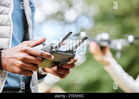 Nahaufnahme von männlichen Händen, die den Drohnen-Controller halten und Tasten drücken, während Sie technische Videoaufnahmen im Freien im Kopierbereich genießen Stockfoto