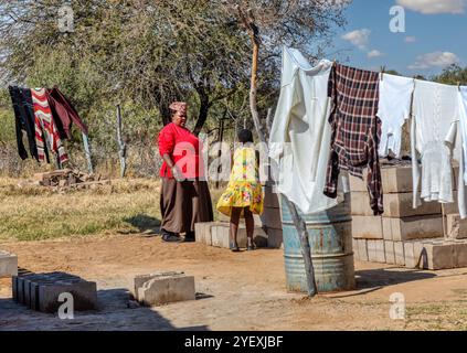 Häusliches Leben in einem afrikanischen Dorf Mutter und Tochter auf dem Hof, Kleidung auf der Wäscheleine, tägliche Arbeit Stockfoto