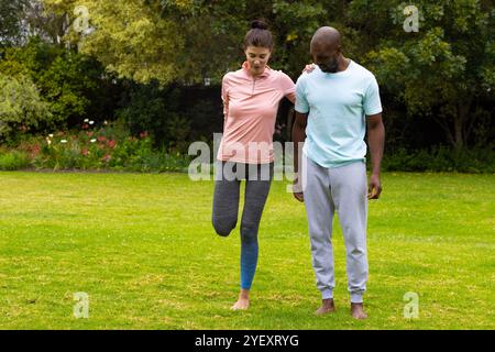 Gemeinsam auf dem Rasen trainieren, multirassisches Paar, das Outdoor-Fitness und Balance-Training macht Stockfoto