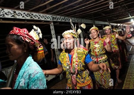 Frauen tanzen in einer Reihe, während sie die Gäste während eines Ökotourismus-Events im Bali Gundi Langhaus der traditionellen Dayak Taman Gemeinde in Sibau Hulu, Putussibau Utara, Kapuas Hulu, West Kalimantan, Indonesien begrüßen. Laut Hernan Vales, Leiter der Abteilung für indigene Völker und Minderheiten der Vereinten Nationen, in einer Veröffentlichung des UN-Menschenrechtsbüros des Hohen Kommissars (OHCHR) im September 2024, sind Stimmen indigener Völker entscheidend für die Förderung ihrer Menschenrechte und ihrer Beteiligung an internationalen Entscheidungen. Stockfoto