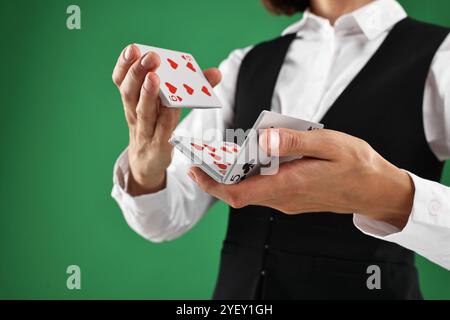 Professioneller Croupier, der Karten auf grünem Hintergrund mischt, Nahaufnahme Stockfoto