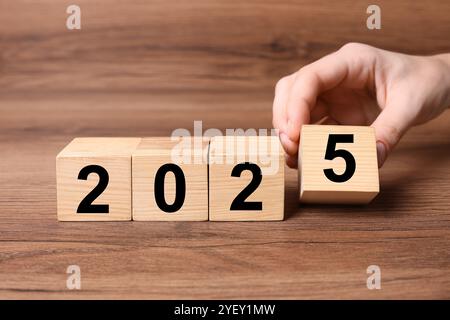 Neujahr 2025. Frau, die Holzwürfel mit Nummer 5 auf den Tisch legt, Nahaufnahme Stockfoto