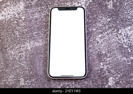 Modernes Smartphone mit leerem weißen Bildschirm auf strukturiertem grauen Hintergrund. Perfekt für die Präsentation von Apps, Websites oder Designs. Stockfoto
