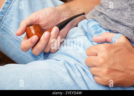 Junger Mann, der rauchende Pfeife in der Hand hält Stockfoto