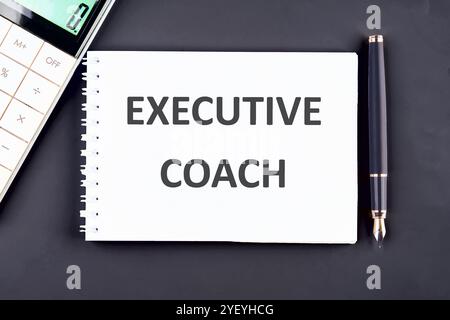 Geschäftskonzept. Der Satz, der Text, das Wort EXECUTIVE COACH sind in einem Notizbuch auf dunkelblauem Hintergrund geschrieben. Stockfoto