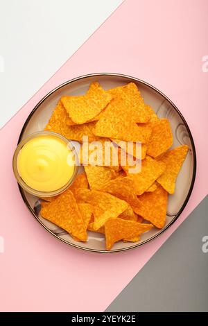 Leckere Nachos mit Käsesauce auf farbenfrohem Hintergrund. Draufsicht Stockfoto