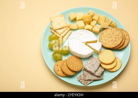 Käseplatte mit verschiedenen Käse und Crackern auf Platte auf beigem Hintergrund. Stockfoto