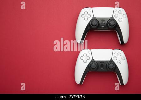 Mykolaiv, UKRAINE - Juli 2024: Weiße Konsole PlayStation 5 und Gamepad auf rotem Hintergrund Stockfoto