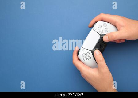 Mykolaiv, UKRAINE - Juli 2024: Weibliche Hand hält einen neuen Sony PlayStation 5-Controller auf Blau Stockfoto