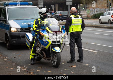 Landkreis Osnabrück, Deutschland 01. November 2024: Im Bild: An einer befahrenen Kreuzung steht ein Polizist mit seinem Polizeimotorrad, neben ihm steht der Leiter Streckendienst mit seiner Warnweste. Im Hintergrund ist ein Polizeifahrzeug mit Schriftzug und Blaulicht zu sehen. Niedersachsen *** Bezirk Osnabrück, Deutschland 01. November 2024 auf dem Bild an einer befahrenen Kreuzung steht ein Polizist mit seinem Polizeimotorrad, daneben steht der Leiter des Streckendienstes mit seiner Sicherheitsweste im Hintergrund ist ein Polizeiauto mit Schriftzug und Blaulicht Niedersachsen zu sehen Copyright: XFotos Stockfoto
