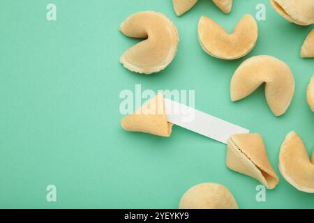 Leckere Glückskekse und Papier mit Vorhersage auf MINT-Hintergrund. Stockfoto