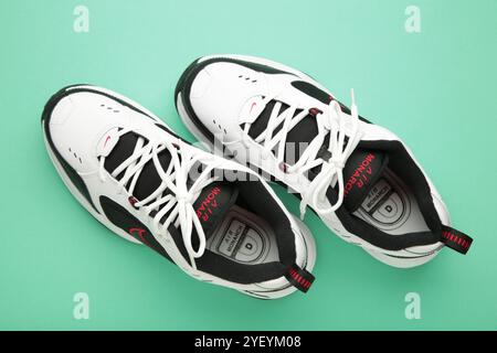 Mykolaiv, UKRAINE - Juli 2024. NIKE AIR MONARCH. Damensportschuhe auf mintfarbenem Hintergrund. Stockfoto