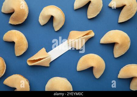 Leckere Glückskekse und Papier mit Vorhersage auf blauem Hintergrund. Stockfoto