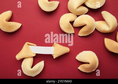 Leckere Glückskekse und Papier mit Vorhersage auf rotem Hintergrund. Stockfoto