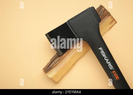 Mykolaiv, UKRAINE - Juli 2024: Axt Fiskars mit Holz auf beigem Hintergrund Stockfoto