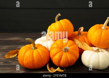 Festliche Herbstdekoration aus Kürbissen und Blättern auf schwarzem Holzhintergrund. Draufsicht Stockfoto