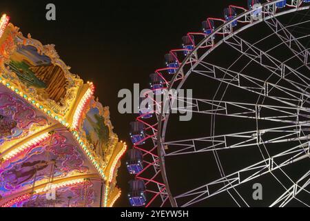 Ein Jahrmarkt bei Nacht mit beleuchtetem Kettenkarussell und Riesenrad, Europa Rad, Fahrten, Wellenflug, Cannstatter Wasen, Volksfest Bad Cannstatt, Stockfoto