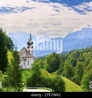 Maria gern Kirche in einer malerischen Berglandschaft, umgeben von dichter grüner Vegetation und sanften Hügeln im Morgennebel, Berchtesgaden, Bava Stockfoto
