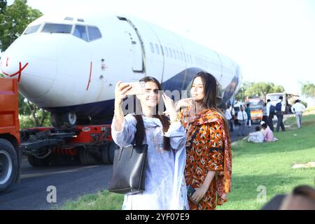 Hyderabad, Sindh, Pakistan. November 2024. Mädchen machen Selfie vor einem Flugzeug, das am Flughafen Hyderabad mit einem Lastwagen über die Autobahn von Karachi erreicht wurde (Credit Image: © Matteo Nardone/Pacific Press via ZUMA Press Wire) NUR REDAKTIONELLE VERWENDUNG! Nicht für kommerzielle ZWECKE! Quelle: ZUMA Press, Inc./Alamy Live News Stockfoto