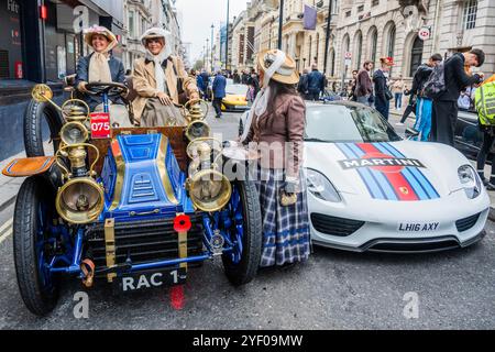 London, Großbritannien. November 2024. 1901 Mors neben einem zeitgenössischen Martini Porsche - es ist 120 Jahre her, dass der Womens Automobile Club gegründet wurde, so dass sie viele Fahrerinnen in historischen Outfits sind - St James's Motoring Spectacle in der Pall Mall, eine Feier des Autofahrens durch die Jahrhunderte und in die Zukunft. Die ausgestellten Fahrzeuge reichen von den bahnbrechenden Grand-Prix-Gewinnern aus den Anfängen des Motorsports bis hin zu den neuesten Supersportwagen mit revolutionären Technologien. Organisiert vom Royal Automobile Club. Er findet am Vorabend des RM Sotheby's London to Brighton Veteran Car Run 2024 f statt Stockfoto