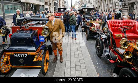 London, Großbritannien. November 2024. Der Besitzer eines 1897er Daimler überprüft das Auto, während Besucher an den wunderschön aufgereihten Veteranenautos spazieren gehen. Das St James's Motoring Spectacle wird als Londons größte, frei zugängliche Autoshow gepriesen, die das Beste aus der Vergangenheit, Gegenwart und Zukunft feiert. Viele der Oldtimer-Modelle nehmen auch an der morgigen Rennbahn Teil. Quelle: Imageplotter/Alamy Live News Stockfoto