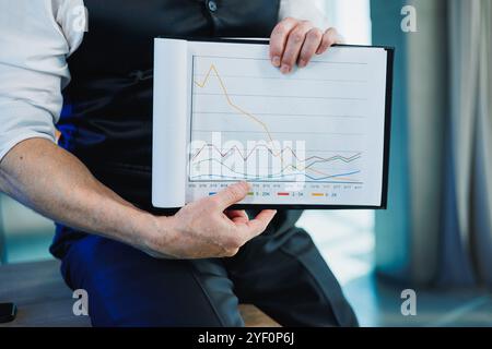 Ein grauer Geschäftsmann, der wichtige Papiere in der Hand hält, ein Mann, der den Vertrag auf Unterschrift überprüft. Arbeiten Sie im Büro Stockfoto