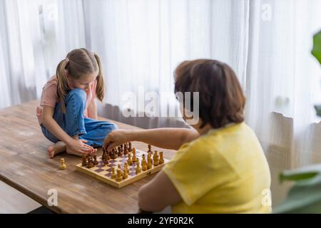 Glückliche Großmutter und Enkelin spielen Schach und schaffen zusammen wertvolle Erinnerungen. Hochwertige Fotos Stockfoto