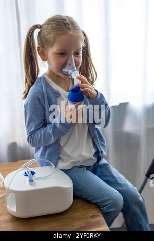 Ein kleines Mädchen atmet zu Hause mit einem Vernebler ein und benutzt Sauerstoffspray für ihren Husten. Hochwertige Fotos Stockfoto