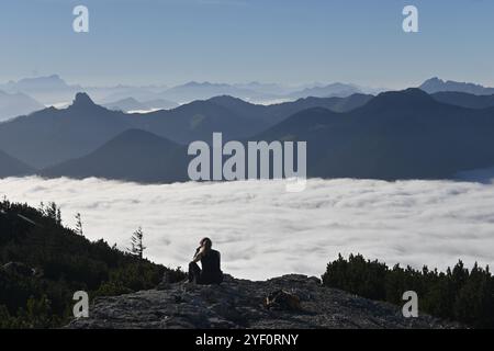 Rottach Egern, Deutschland. November 2024. Ein Wanderer sitzt auf dem Gipfel des Wallbergs und blickt über das nebelbedeckte Tal. Quelle: Katrin Requadt/dpa/Alamy Live News Stockfoto