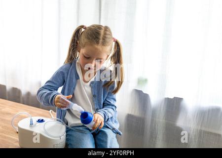 Zu Hause atmet ein 5-jähriges Mädchen durch einen Vernebler und konzentriert sich auf ihre Inhalationstherapie. Hochwertige Fotos Stockfoto