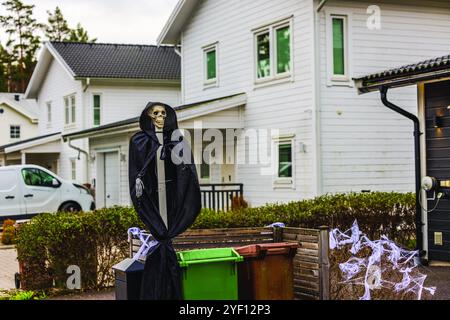 Skelett Halloween Dekoration in schwarz getarnt in der Nähe von Wohnbehältern, umgeben von Kunstspinnweben. Stockfoto