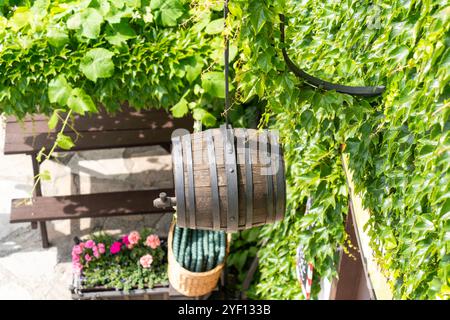 Hölzernes Tonnenschild hängt an der Wand eines alten Landhauses, umgeben von Efeu und Blumen Stockfoto