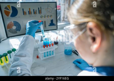 Ein engagierter Wissenschaftler führt ein Experiment in einem gut ausgestatteten Labor durch, umgeben von einer Vielzahl von farbenfrohen Reagenzgläsern Stockfoto