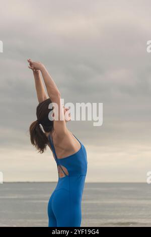 Sportliche Schwimmerin, die am Strand einen Arm über dem Kopf streckt Stockfoto