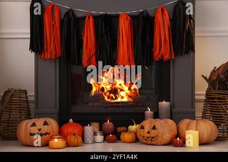 Kürbisse und brennende Kerzen in der Nähe des Kamins drinnen. Halloween Dekoration Stockfoto