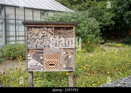 Naturgarten mit Blumenbeeten, Gewächshaus und Insektenhotel Stockfoto