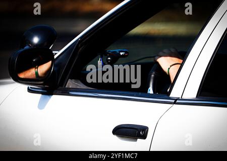 Hand auf dem Lenkrad durch das offene Fenster eines weißen Kronprinzessin Victoria Police Interceptor P7B Stockfoto