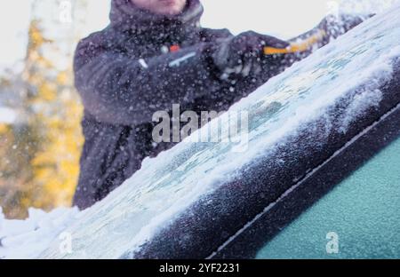 Mann kratzt Schnee von der Windschutzscheibe des Autos, Kopierraum Stockfoto