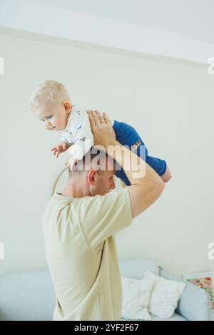 Der junge lächelnde Vater spielt mit seinem neugeborenen Sohn. Dad und kleiner Sohn. Stockfoto