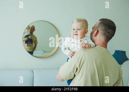 Der junge lächelnde Vater spielt mit seinem neugeborenen Sohn. Dad und kleiner Sohn. Stockfoto